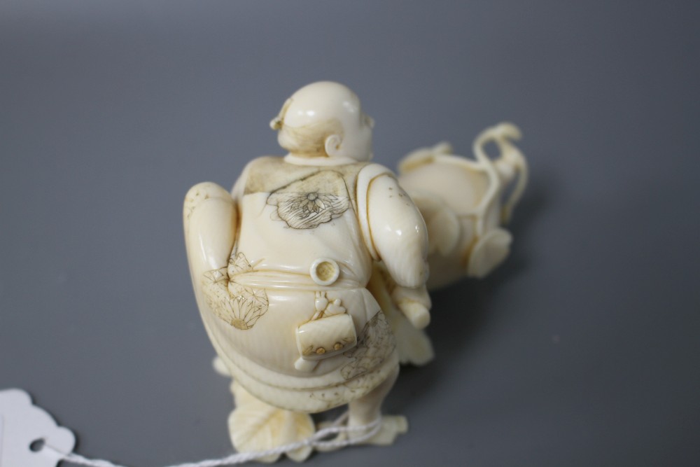 A Japanese Meiji period ivory okimono carved with a man carving a giant gourd, signed, length 10cm, height 7cm